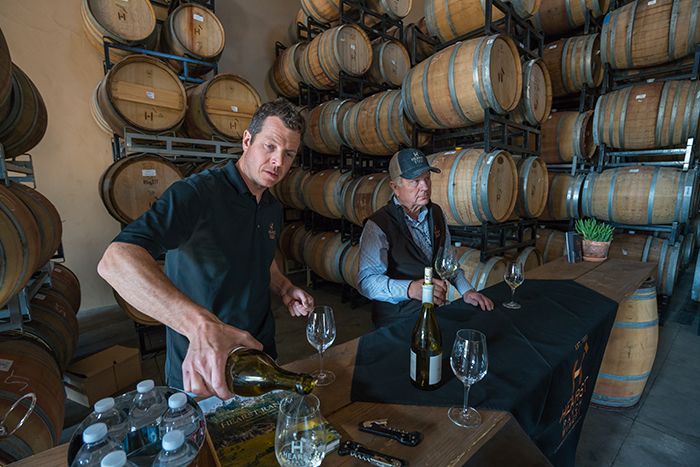 El enólogo Soren Christensen y el propietario Jim Saunders sirven una degustación de Chardonnay en la sala de barricas del Saunders Vineyard en Paso Robles, California.