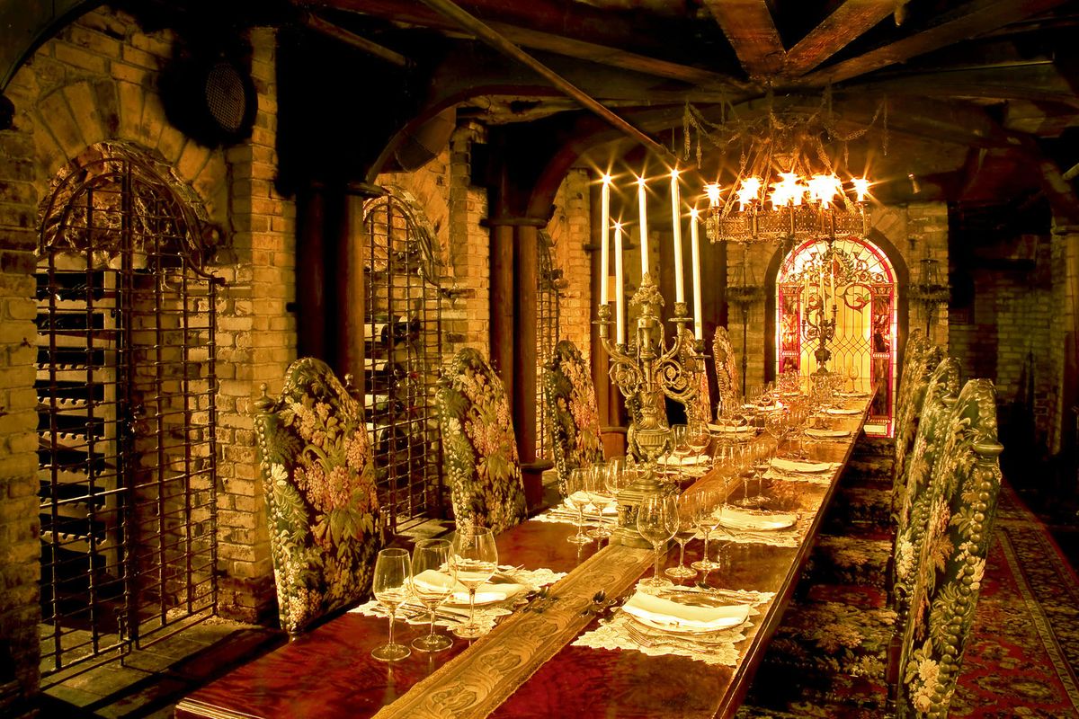 중앙에 긴 테이블이 있고 조명이 켜진 촛대가있는 고딕 양식의 와인 저장고