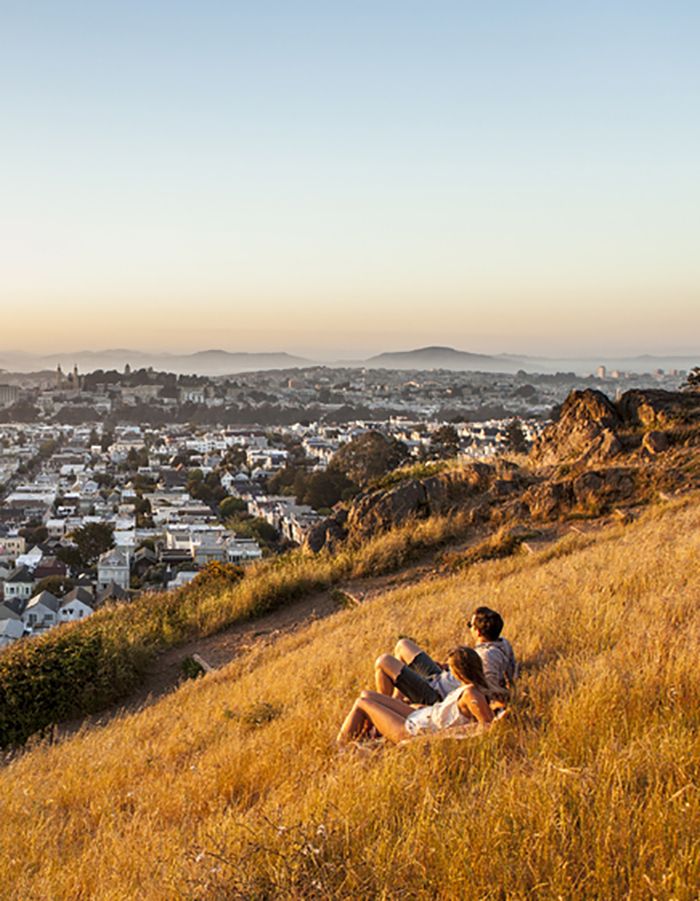सैन फ्रांसिस्को, CA में ट्विन चोटियों पर सूर्यास्त देख रहे लोग
