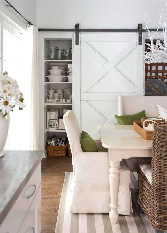 חדר אוכל לבן עם שטיח פסים וכריות כיסא ירוקות