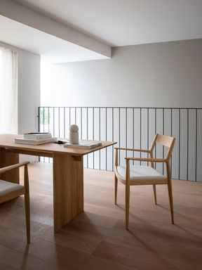 كرسي خشبي حديث في بيئة مزينة محايدة مع جدار مطلي باللون الأبيض