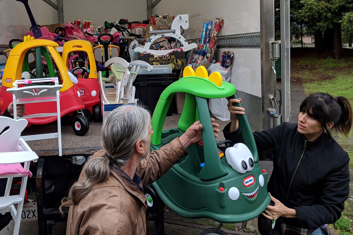 Un hombre y una mujer descargando un camión lleno de juguetes para niños pequeños