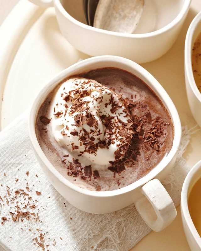Doble chocolate caliente en taza blanca con crema batida y virutas de chocolate
