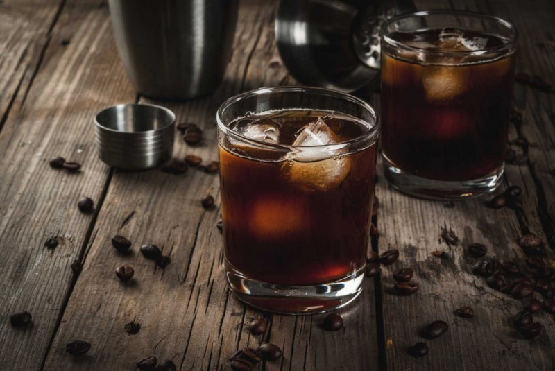   Cocktail rusesc negru pe masă de lemn cu boabe de cafea înconjurătoare
