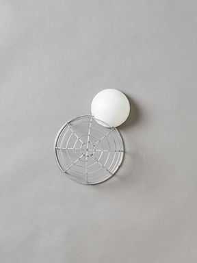 Pequena bola de espuma branca colada na lateral de uma grande esfera de fio prateado
