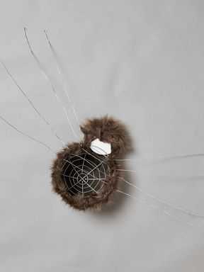 Umjetno smeđe krzno prekriva žičani okvir i kuglu od pjene koja izgleda poput pauka