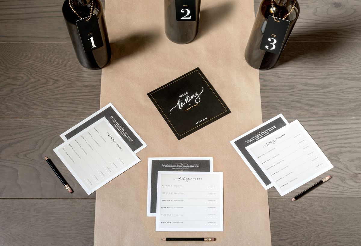 Fotografie tří neoznačených lahví vína a tří karet připravených pro hráče ochutnávky vín