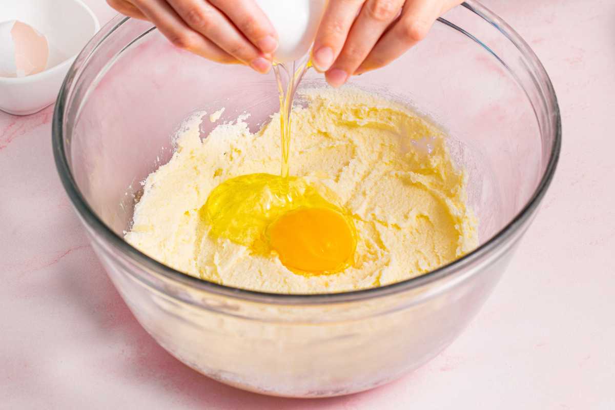 aggiungendo le uova alla crema di burro e zucchero in una ciotola
