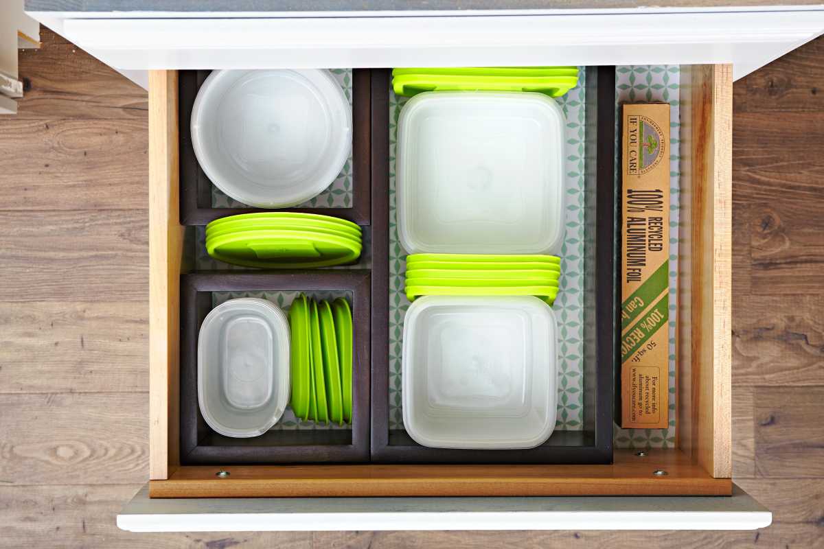 Contenedores de almacenamiento de alimentos con tapa verde organizados en el cajón
