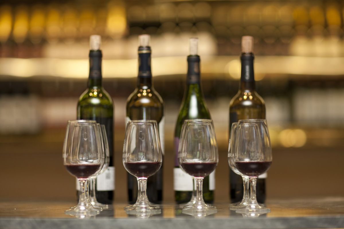 Sarkanvīna glāzes un vīna pudeles uz vīna pagraba letes