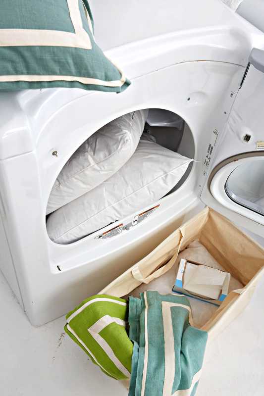 Secadora con almohadas verdes y cesto para la ropa.