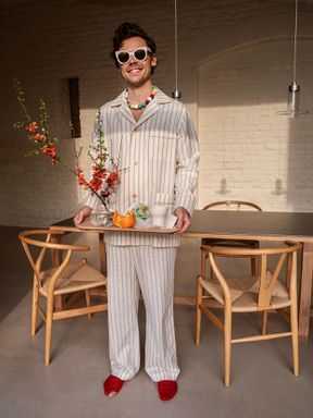 Photographie de Harry Styles en pyjama et tenant un plateau