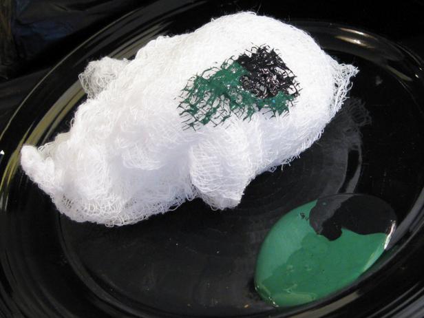 Usando uma esponja, esponja de maquiagem ou pano de algodão, passe suavemente uma mistura de tinta verde escura e preta sobre a superfície da estátua. Deixe um pouco da tinta de metal aparecendo. Deixe secar.