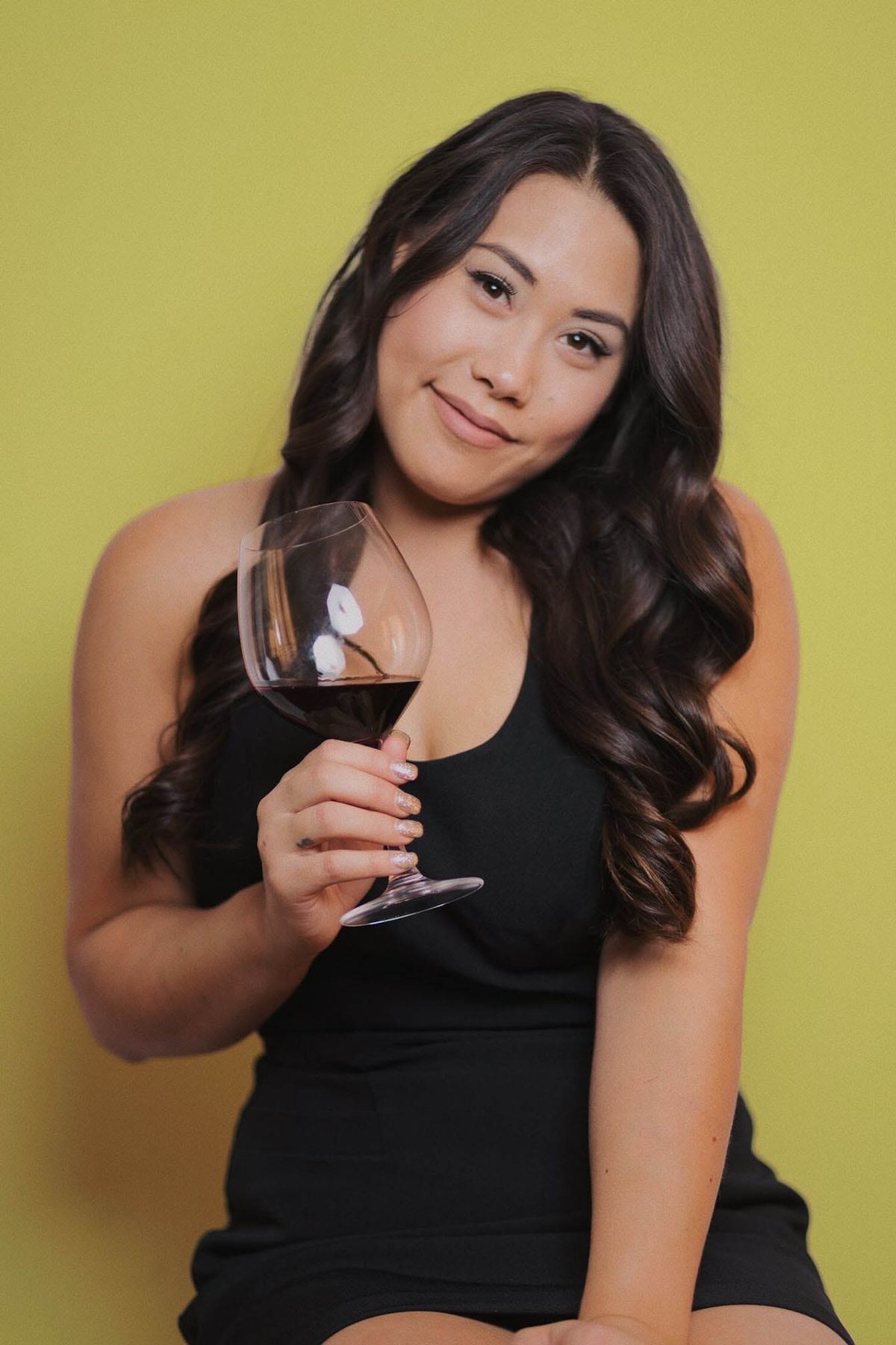 Cristie Norman hält Wein auf gelbem Hintergrund