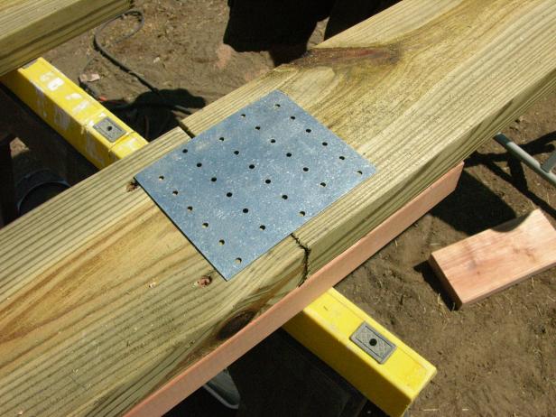 Después de cortar varias tablas a medida, atornille la madera tratada y la secuoya para formar tablas perimetrales de doble espesor. Clave las bridas de acero del soporte para dar soporte lateral.