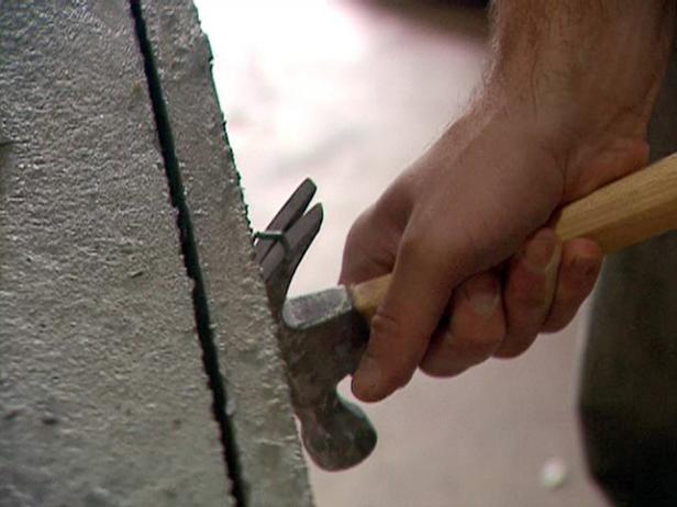 Utilice con cuidado un martillo y los tornillos nuevos para hacer palanca en ambos lados de la losa de hormigón.