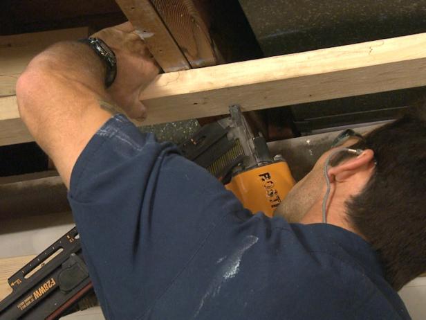 Mężczyzna używający narzędzia do montażu płyt sufitowych w tym projekcie naprawy domu.