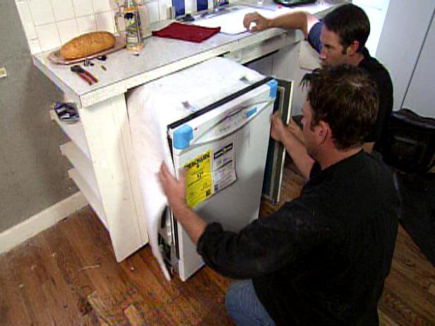 Джош Темпл, хозяин Disaster House, наблюдает, как посудомоечная машина устанавливается на кухне.