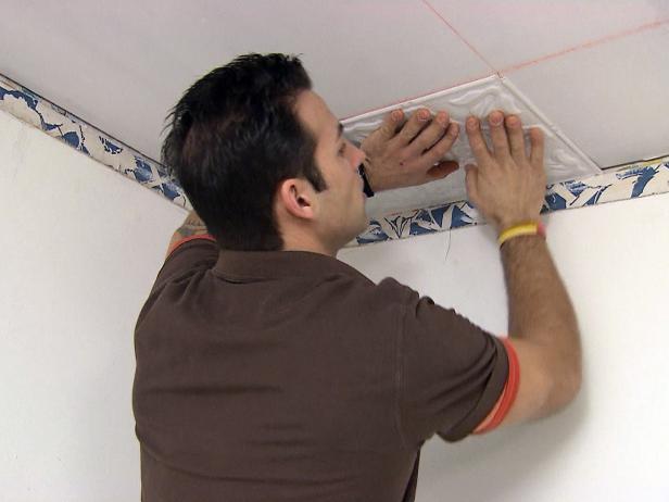 Marc installeert tinnen plafondtegels in de kamer van dit woningverbeteringsproject.