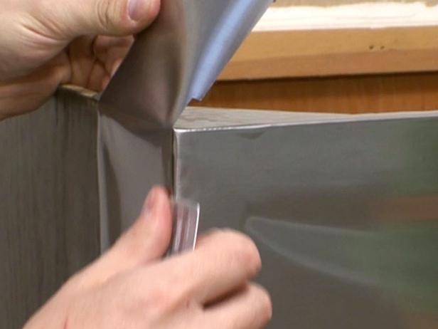 Usando una navaja para cortar el borde del material para cubrir el tocador viejo.