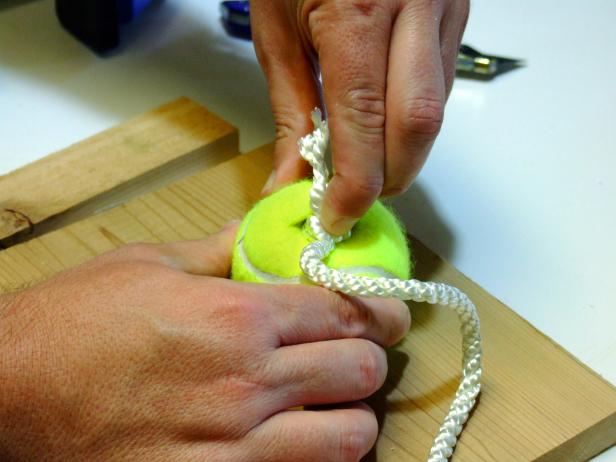 Empuja cada extremo anudado en la hendidura de las pelotas de tenis. Asegúrese de que el nudo esté completamente insertado y tire ligeramente para apretar el nudo contra el interior de la bola.
