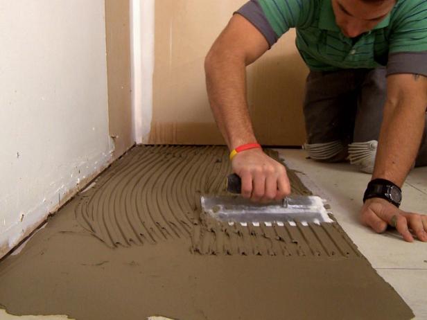 Esparcir mortero en el piso para agregar baldosas de tablones en este proyecto de mejoras para el hogar.