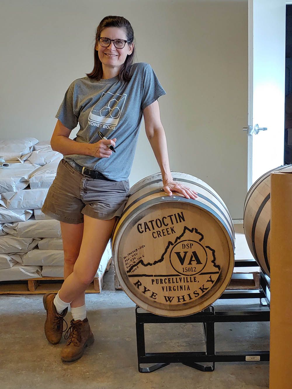 Becky Harris de Catoctin Creek Distilling Company de pie junto a barriles de whisky de centeno