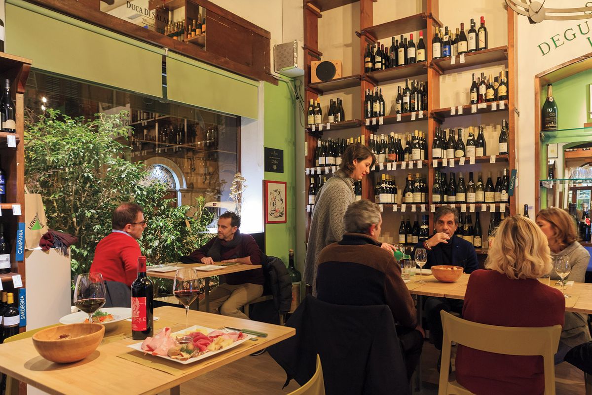 Una fotografía de gente comiendo y bebiendo en Enoteca Picone en Italia.