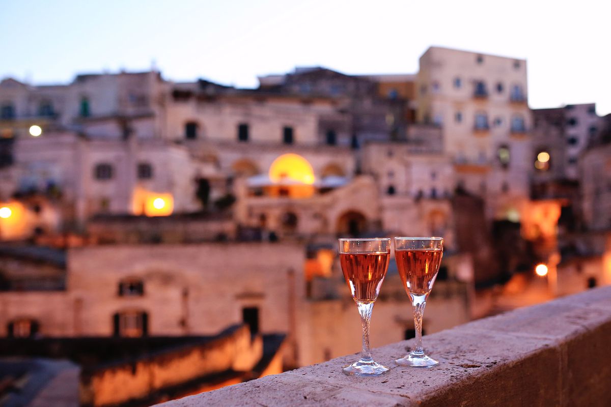 Dua gelas anggur mawar di balkoni dengan pemandangan malam ke kota kuno