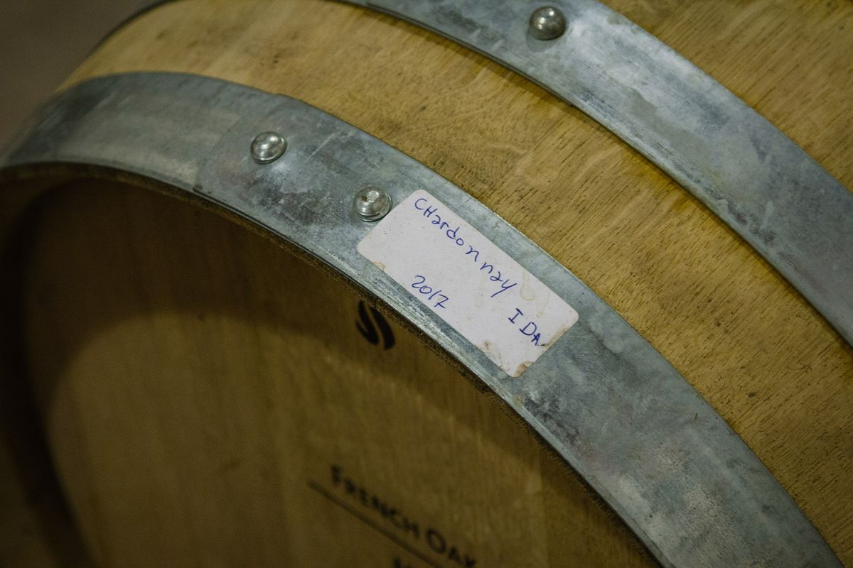 Un barril de vino de madera con bandas de metal yace de lado. El barril está etiquetado con una etiqueta adhesiva blanca que dice