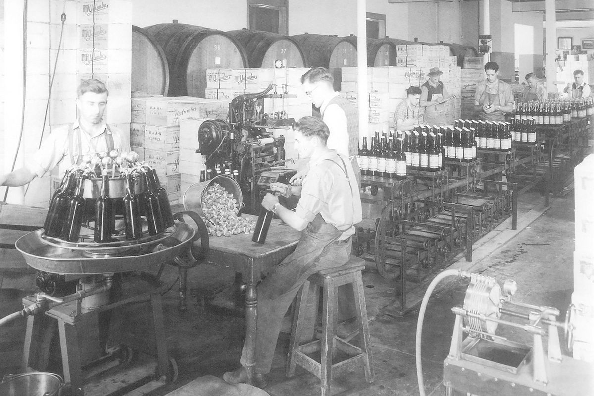 शराब की बोतलों को भरते हुए एक असेंबली लाइन की पुरानी तस्वीर