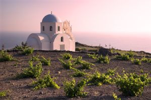 โบสถ์และไร่องุ่นเล็ก ๆ ยามพระอาทิตย์ตกเหนืออ่าว Mesa Pigadia ใกล้ Akrotiri, Santorini, หมู่เกาะ Cyclades, กรีซ / ภาพโดย Mick Rock, Cephas