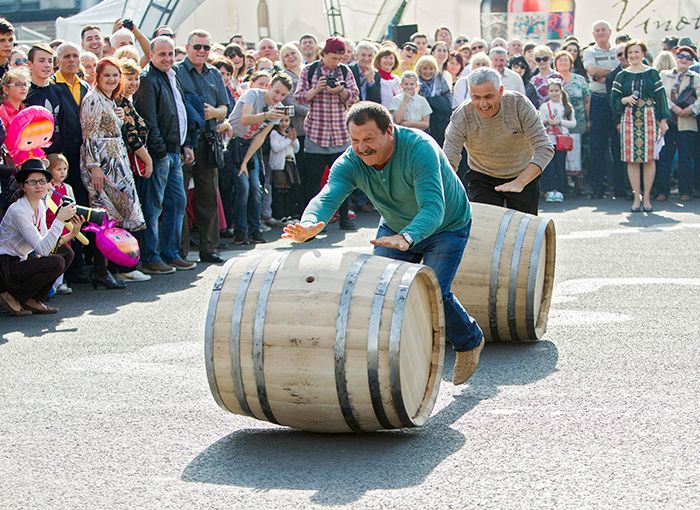 Deux hommes dans un concours de roulage de tonneaux de vin lors de la célébration de la Journée nationale du vin sur la grande place de l