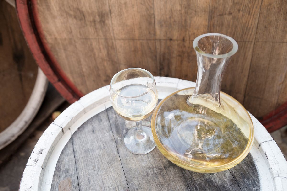 Pretočeno bijelo vino i vino u čaši na vrhu bačve