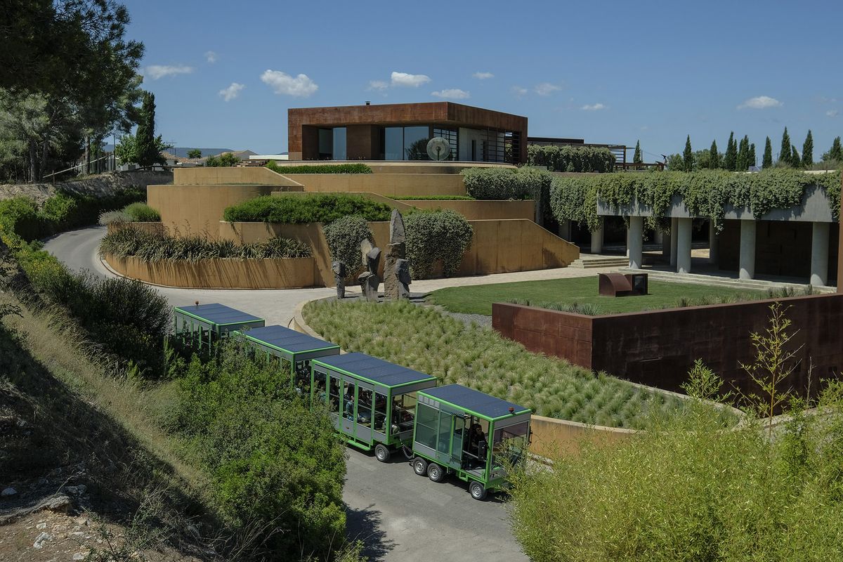 Groene tram die een oprit afgaat voor een moderne wijnmakerij