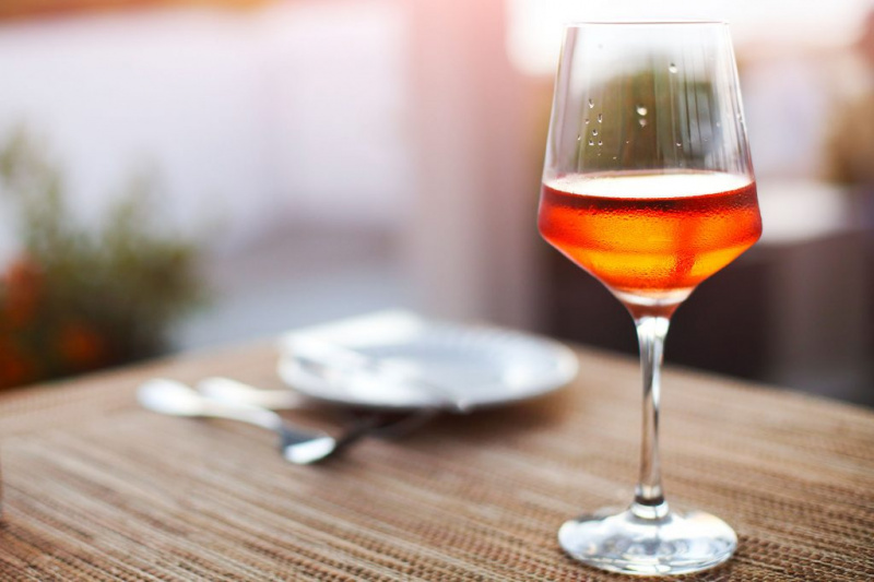   Sklenka oranžového vína sedí na stole